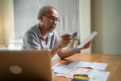 photo of male looking at a paper with his credit card in his hand