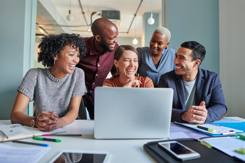 Photo of diverse group of people around a computer